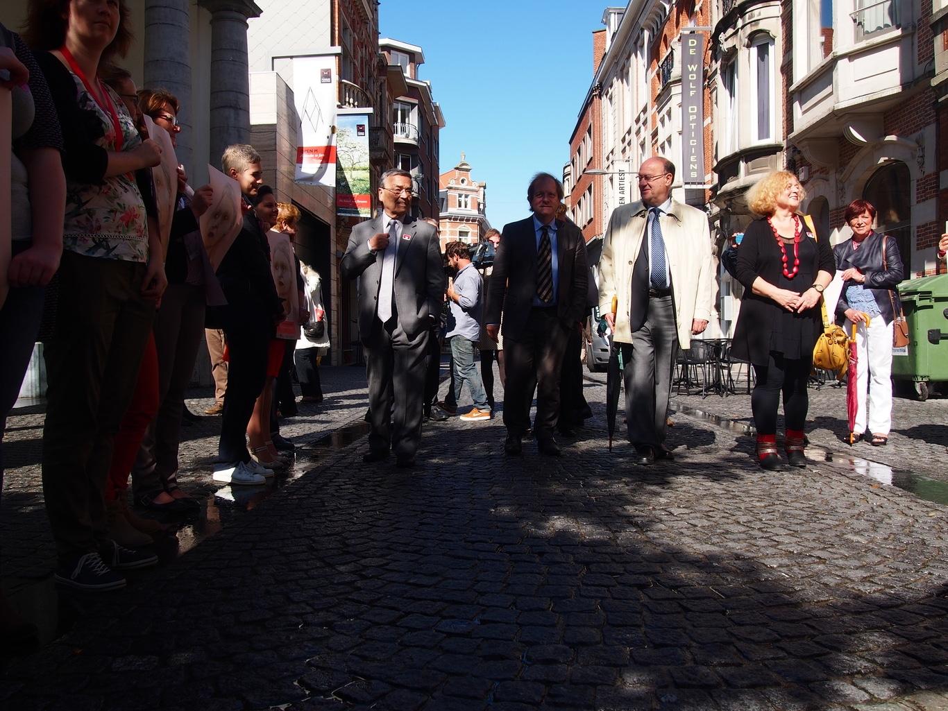 Louis Tobback, Rik Torfs, Denise Vandevoort en een honderdtal genodigden wandelen achterwaarts naar het museum ter gelegenheid van de opening. 