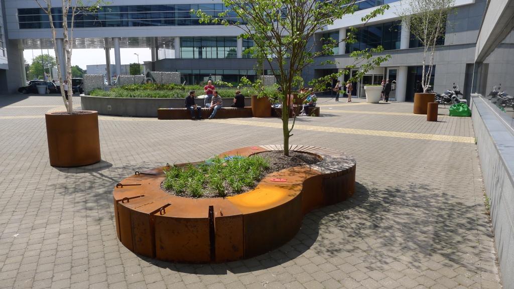 Het is een verrassende plek geworden om even te chillen met meubilair op maat zoals deze plantenbak uit cortenstaal met geïntegreerde zitbank. Berken met opvallende witte stammen en ginkgo’s geven een apart karakter.nn